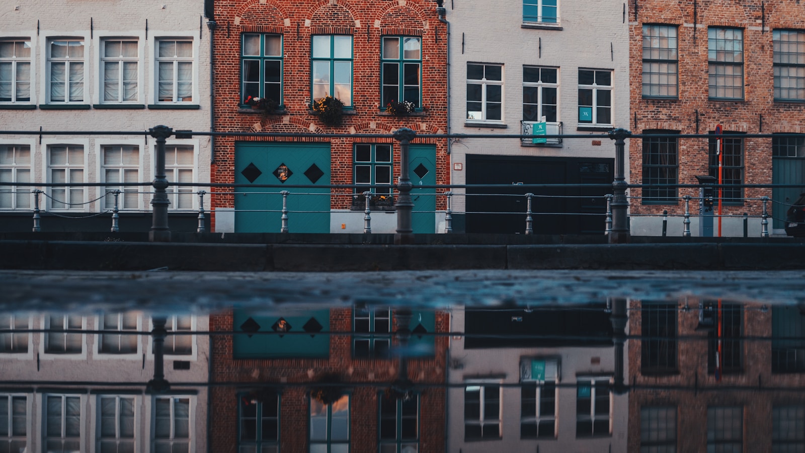 Te-koop-bord voor een Belgische rijwoning in een stedelijke straat, zacht ochtendlicht